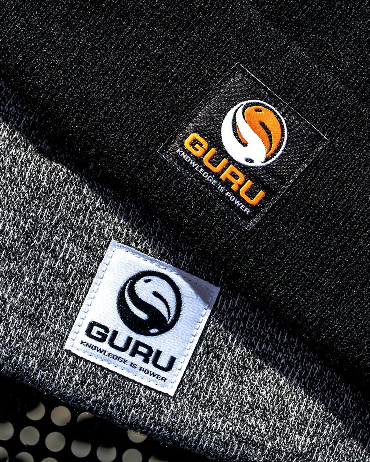 Guru Black Patch Beanie – detailvergelijking van de zwarte muts met oranje patch en een grijs gemêleerde muts met witte patch