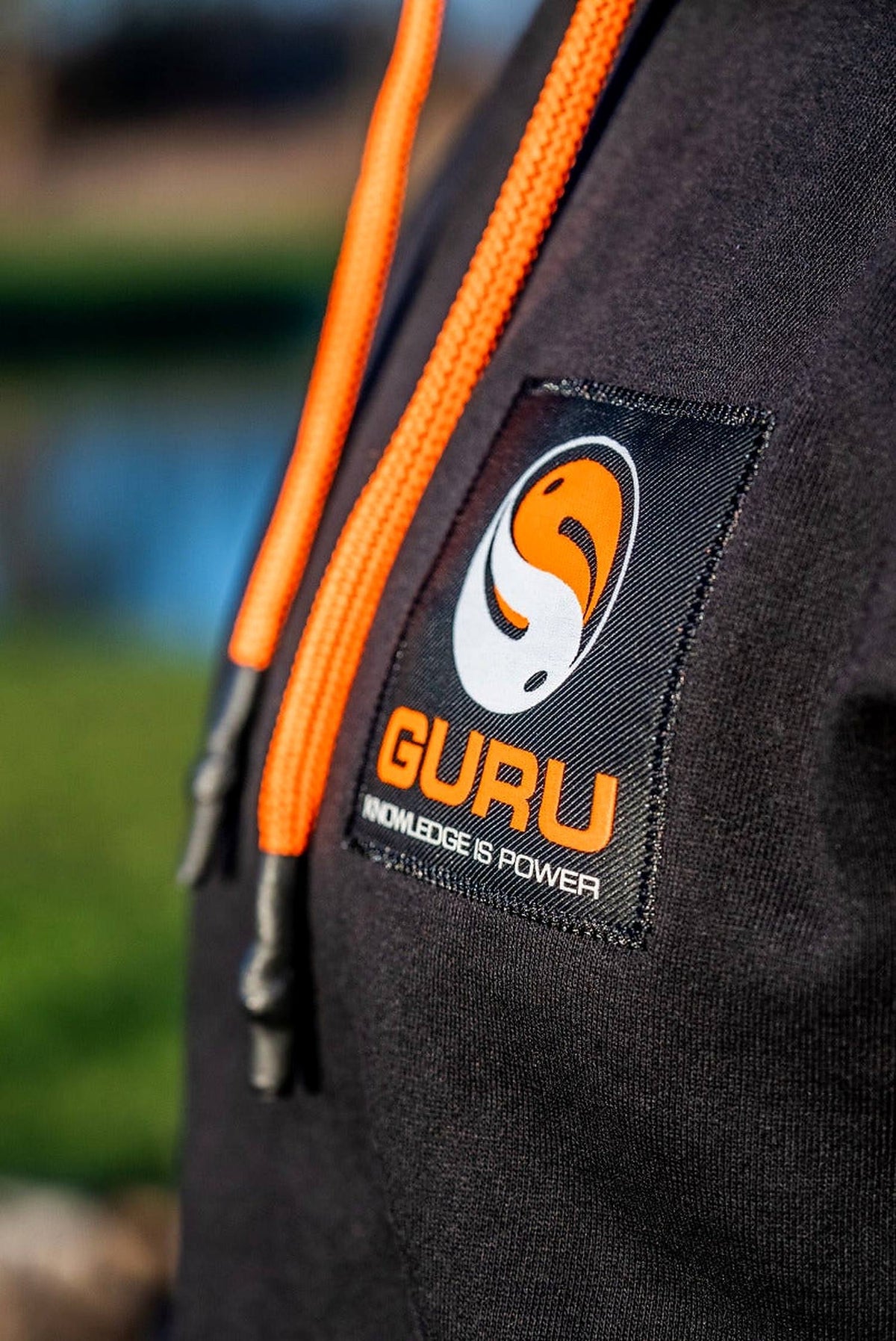 Guru Black Patch Hoodie – close-up van de Guru-borstpatch en oranje koorden