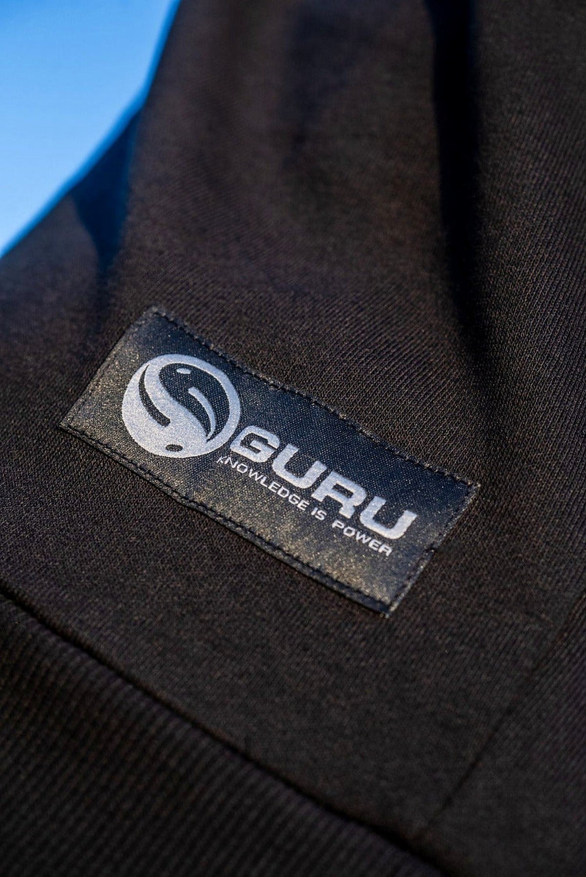 Guru Black Patch Hoodie – close-up van het Guru-label en de ribboord aan de onderzijde