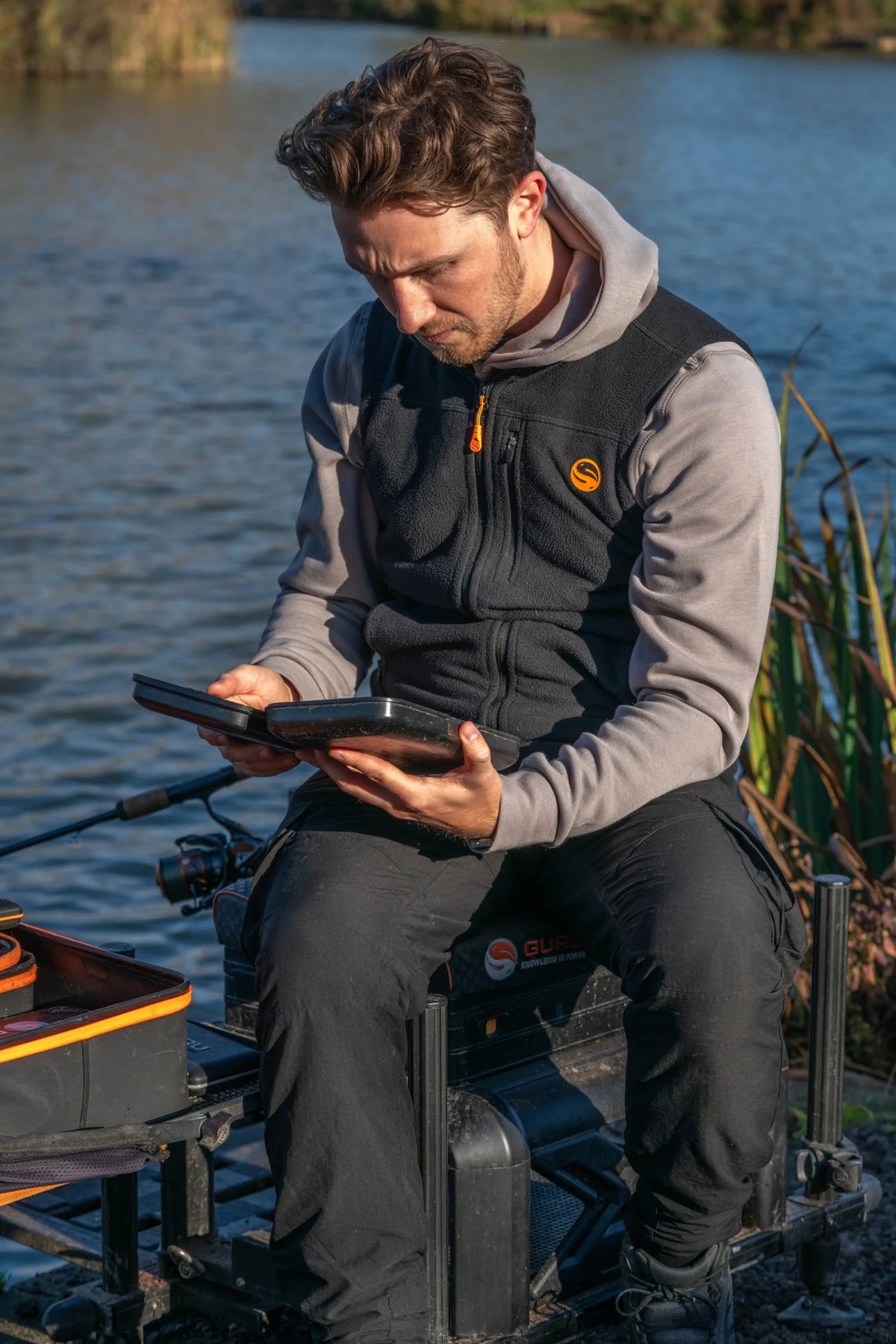 Guru Fleece Gilet Black - gedragen over grijze hoodie aan de waterkant