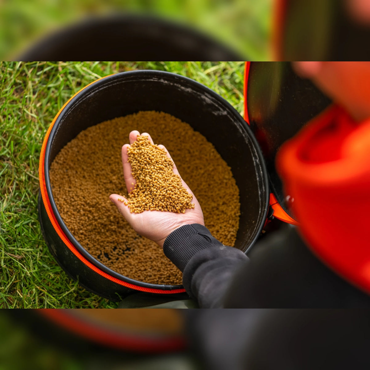 Guru Fusion Bucket10L – hand met grondvoer boven de geopende emmer