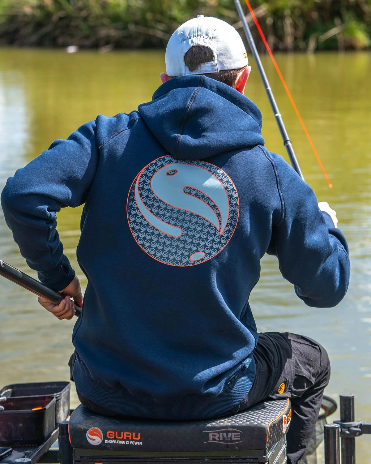 Guru Hoodie Navy – donkerblauwe hoodie gedragen aan waterkant, achteraanzicht