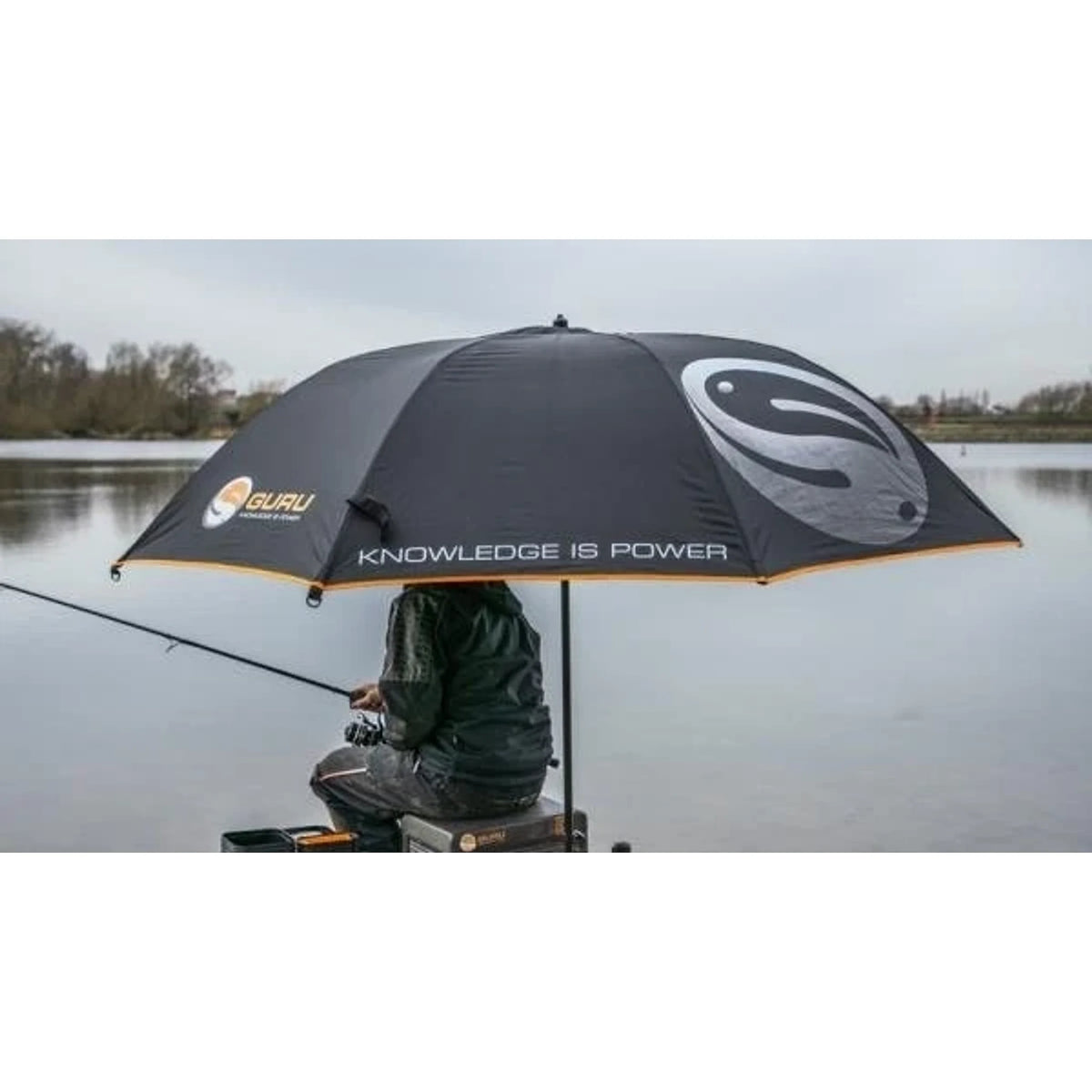 Guru Large Umbrella als beschutting voor visser op zitkist aan het water