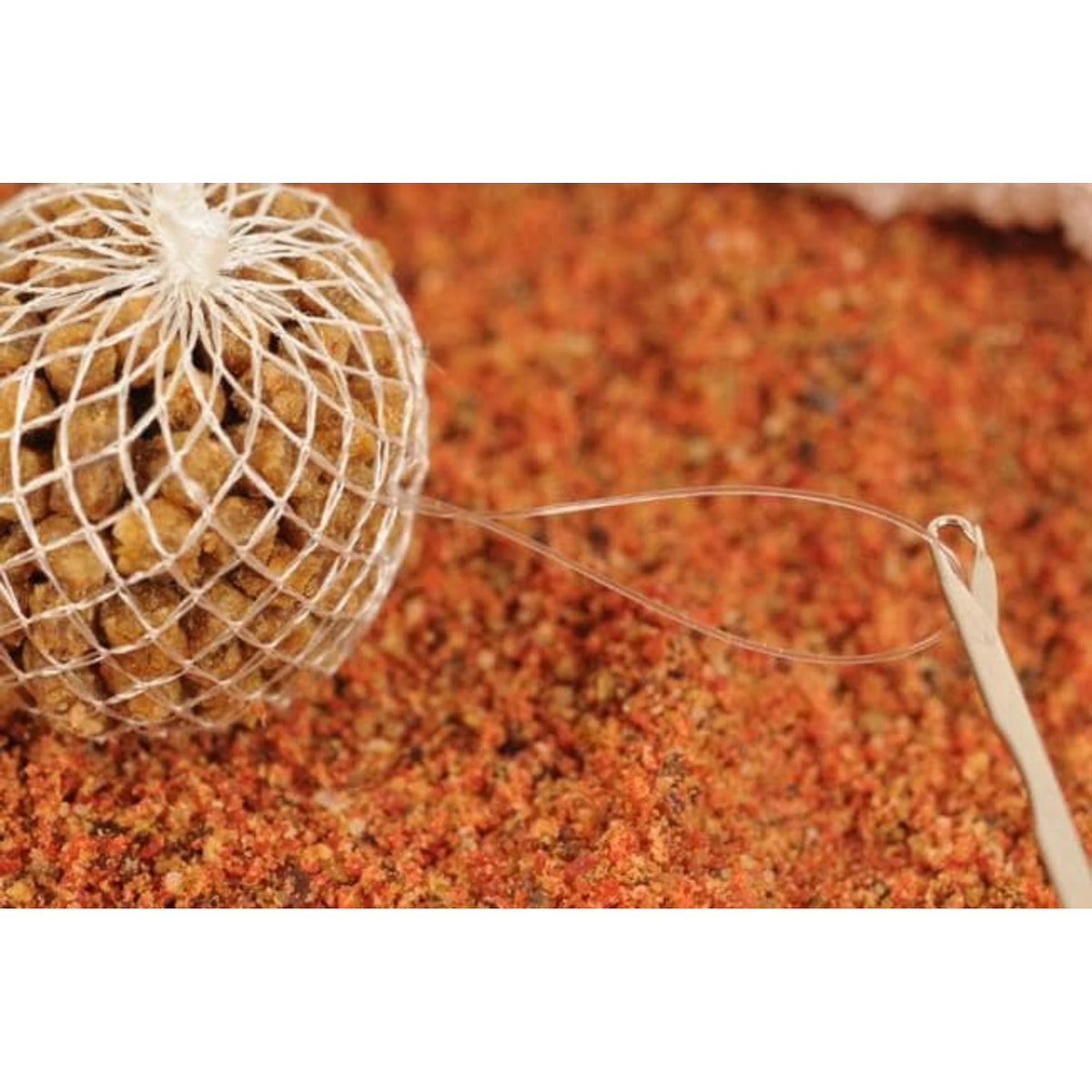 Guru Speedmesh Needle met onderlijnlus naast PVA-zakje met pellets