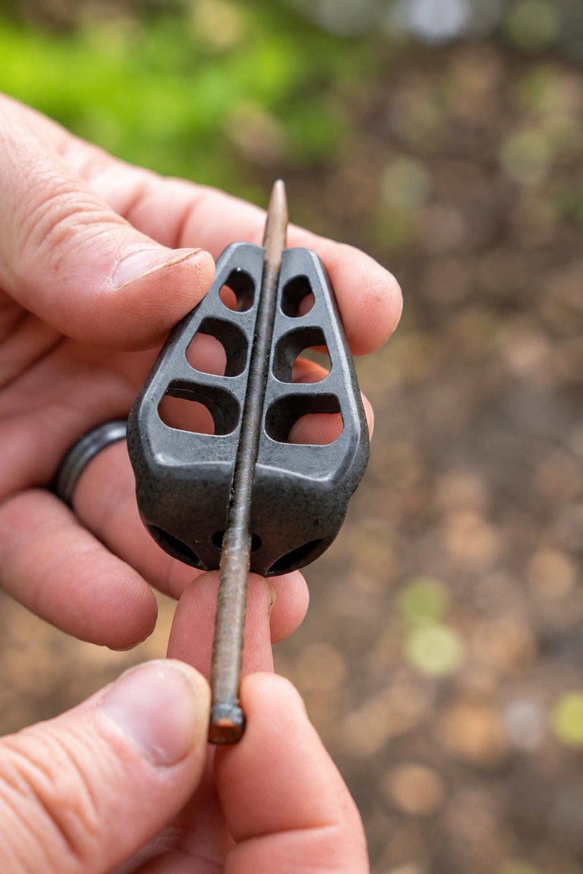 Korum Arrowhead Distance Method Feeder in de hand met doorlopende steel en zes openingen
