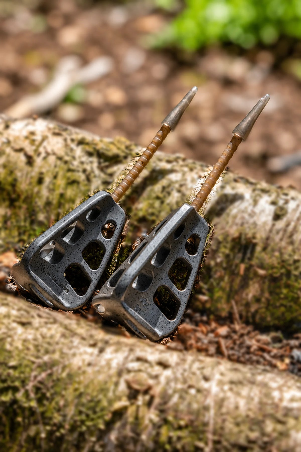 Twee Korum Arrowhead Distance Method Feeders met lange stelen tegen een boomstam
