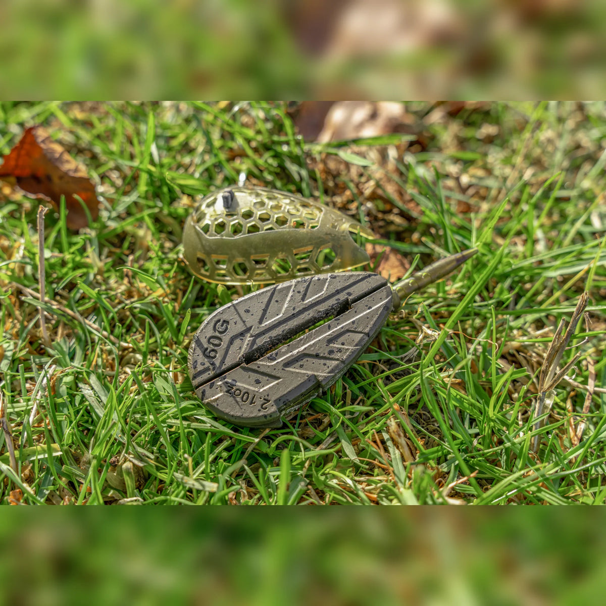 Korum Camo Grub Feeder – geopende standaardkorf met onderzijde op gras
