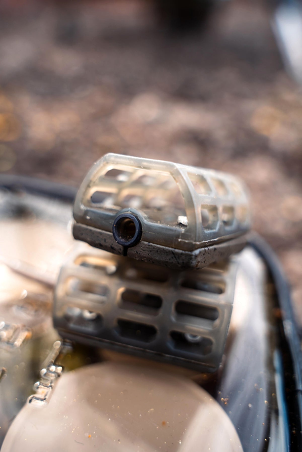 Twee lege Korum Camo Inline Cage-voerkorven met open camouflagekooi op een aasdoos