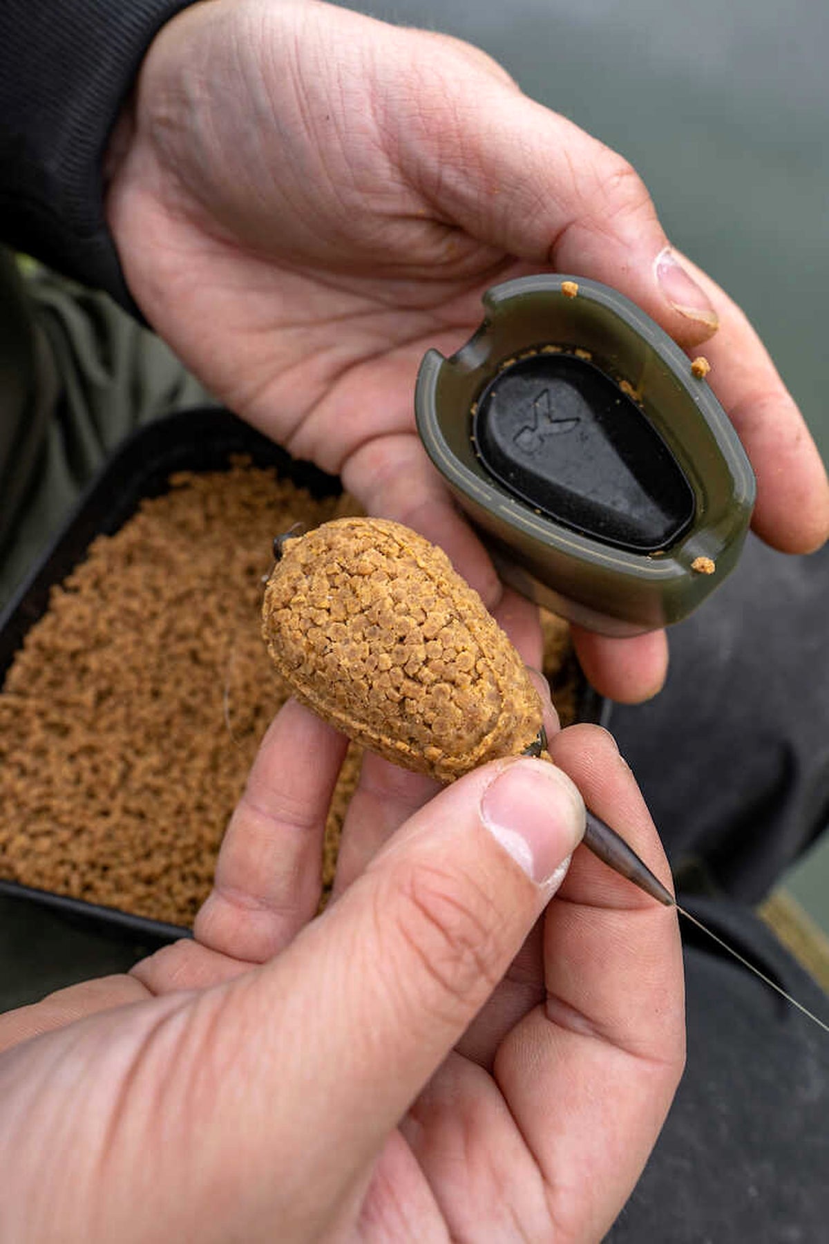 Korum Camo Method Feeder gevuld met pellets, naast de gebruikte methodmal in de hand