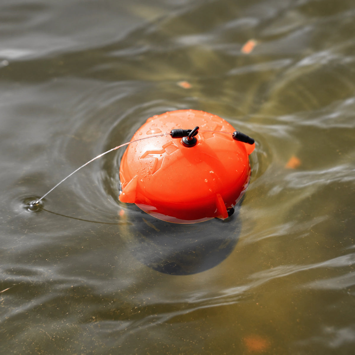 Korum Floating Feeder K0320069 met oranje kap en vislijn aan het wateroppervlak