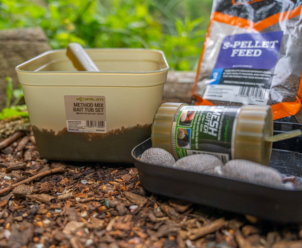Korum Method Mix aasbak met schep en pellets naast een binnentray met gevulde PVA-zakjes