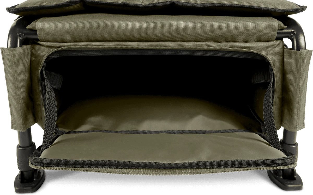 Korum Progress Ruckchair Standard met geopend voorvak onder de zitting, neergeklapte klep en twee zichtbare poten