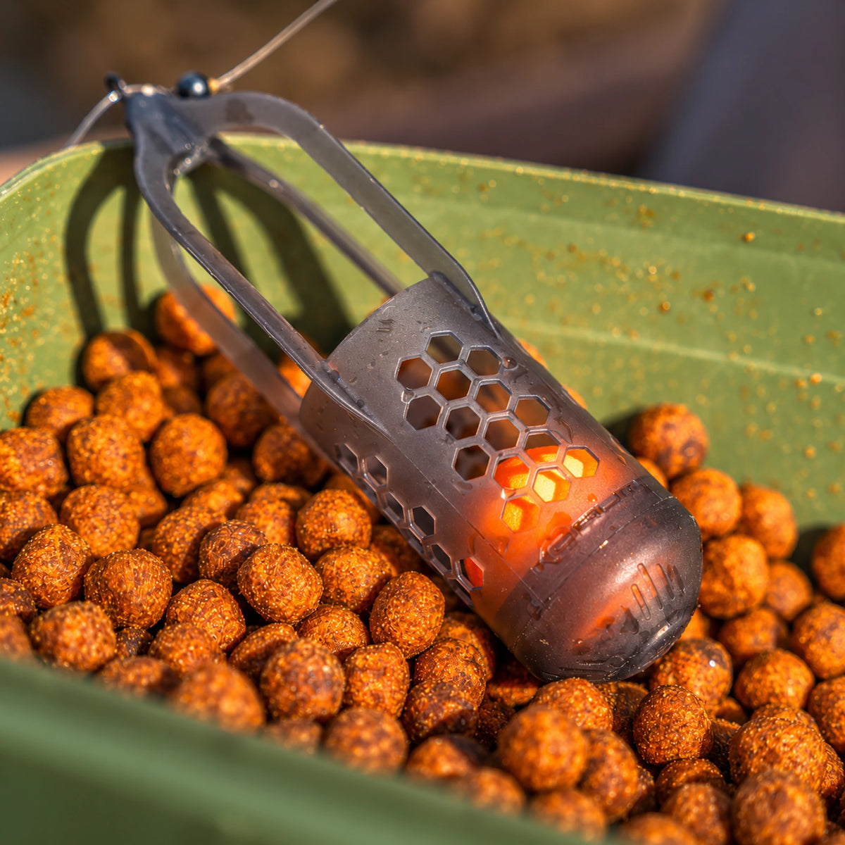 Korum Surface Feeder Float K0320112 – liggende voerkorf met ingedrukte oranje EVA-bal in een aasbak met pellets