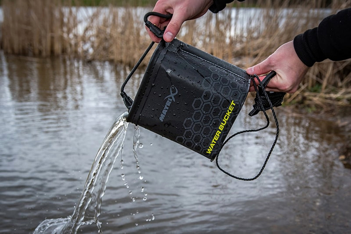 Water uitgieten uit de Matrix EVA Water Bucket, met de koordhaspel in de andere hand