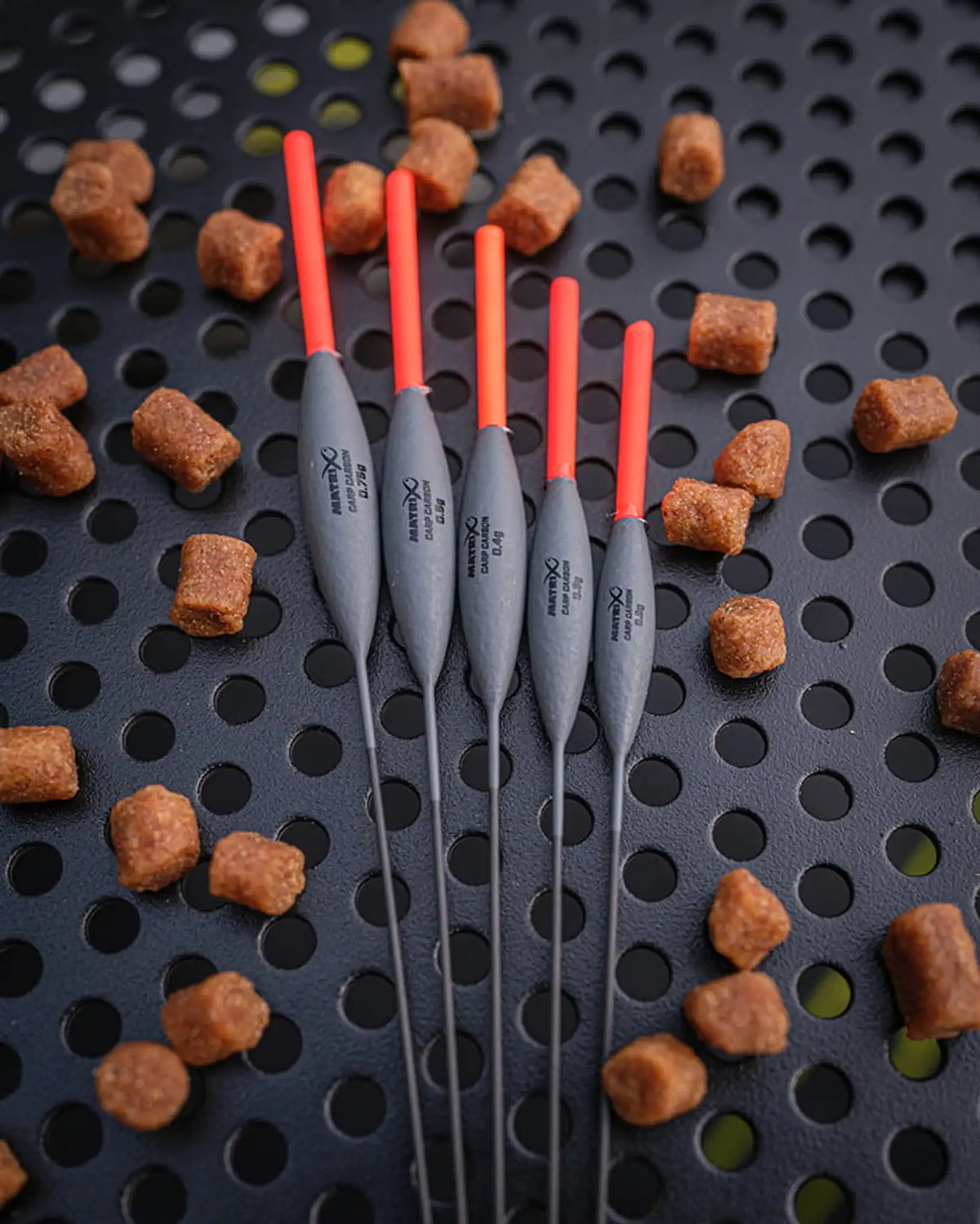 Matrix Carp Carbon Pole Floats, vijf dobbers naast elkaar op een aastafel met pellets