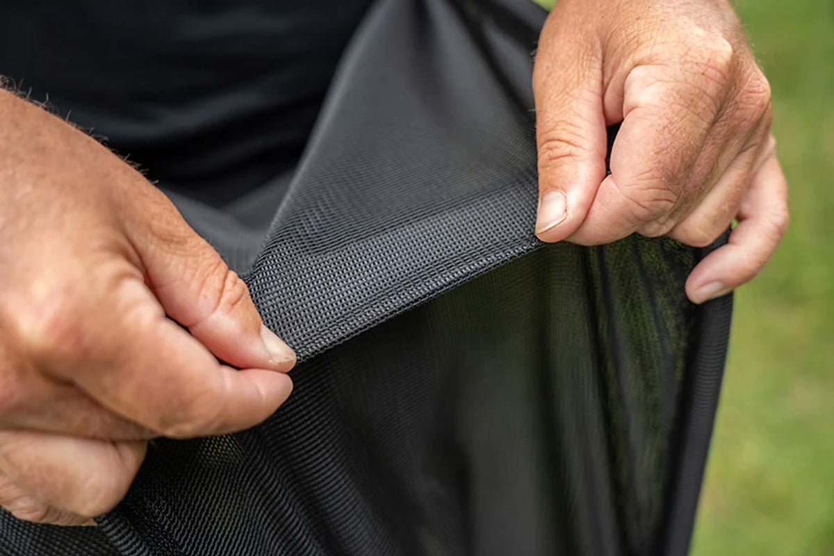 Visser toont het visveilige gaas van het Matrix Carp Safe Keepnet tussen beide handen
