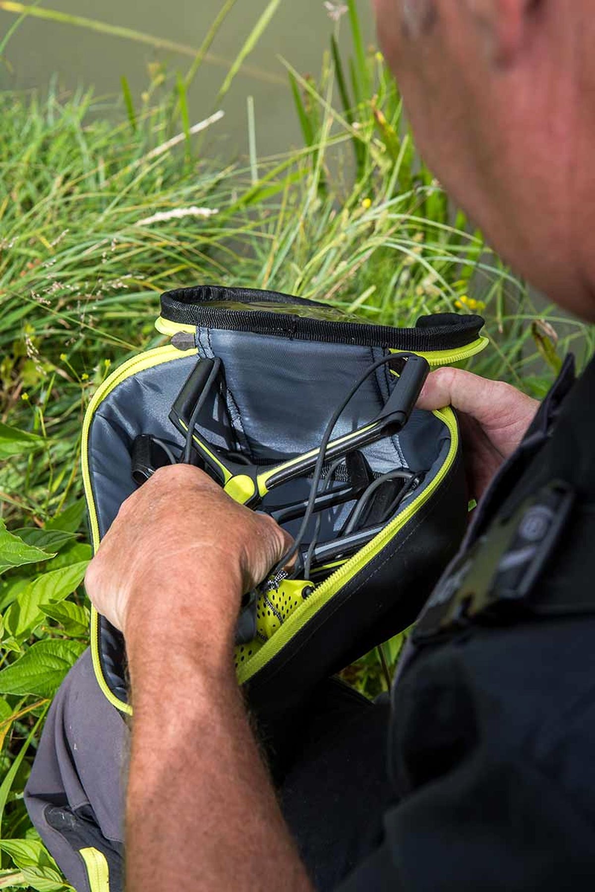 Visser neemt een katapult uit de open Matrix Catapult Case aan de waterkant