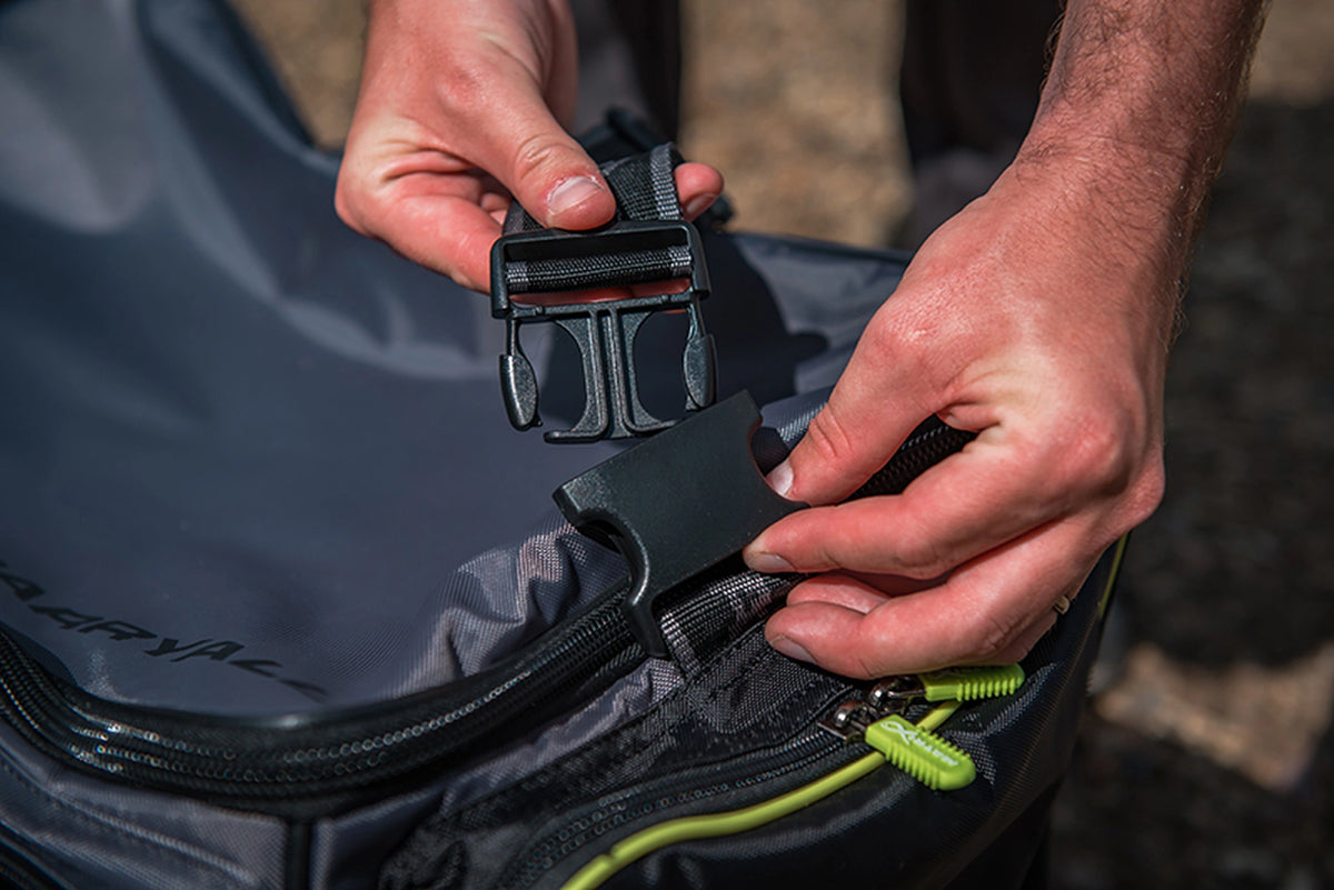 Matrix Ethos Large Carryall – handen tonen de geopende zwarte klikgesp waarmee de schouderriem is bevestigd