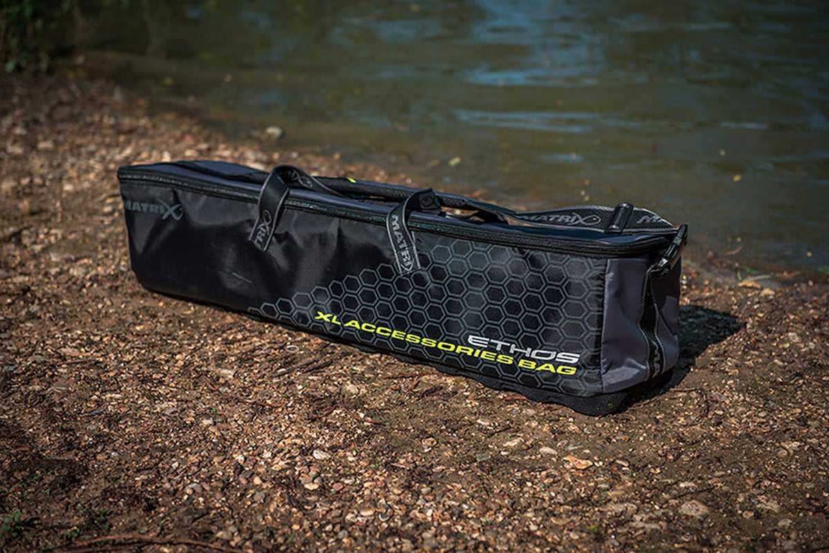 Matrix Ethos XL Accessories Bag – gesloten accessoiretas met honingraatpatroon op de oever aan het water