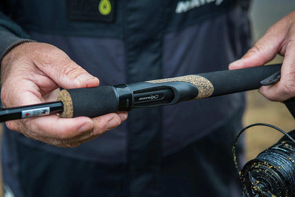 Matrix Ethos XR-S Feeder Rod – visser toont het zwarte handvat en de molenhouder met Matrix-logo tussen beide handen
