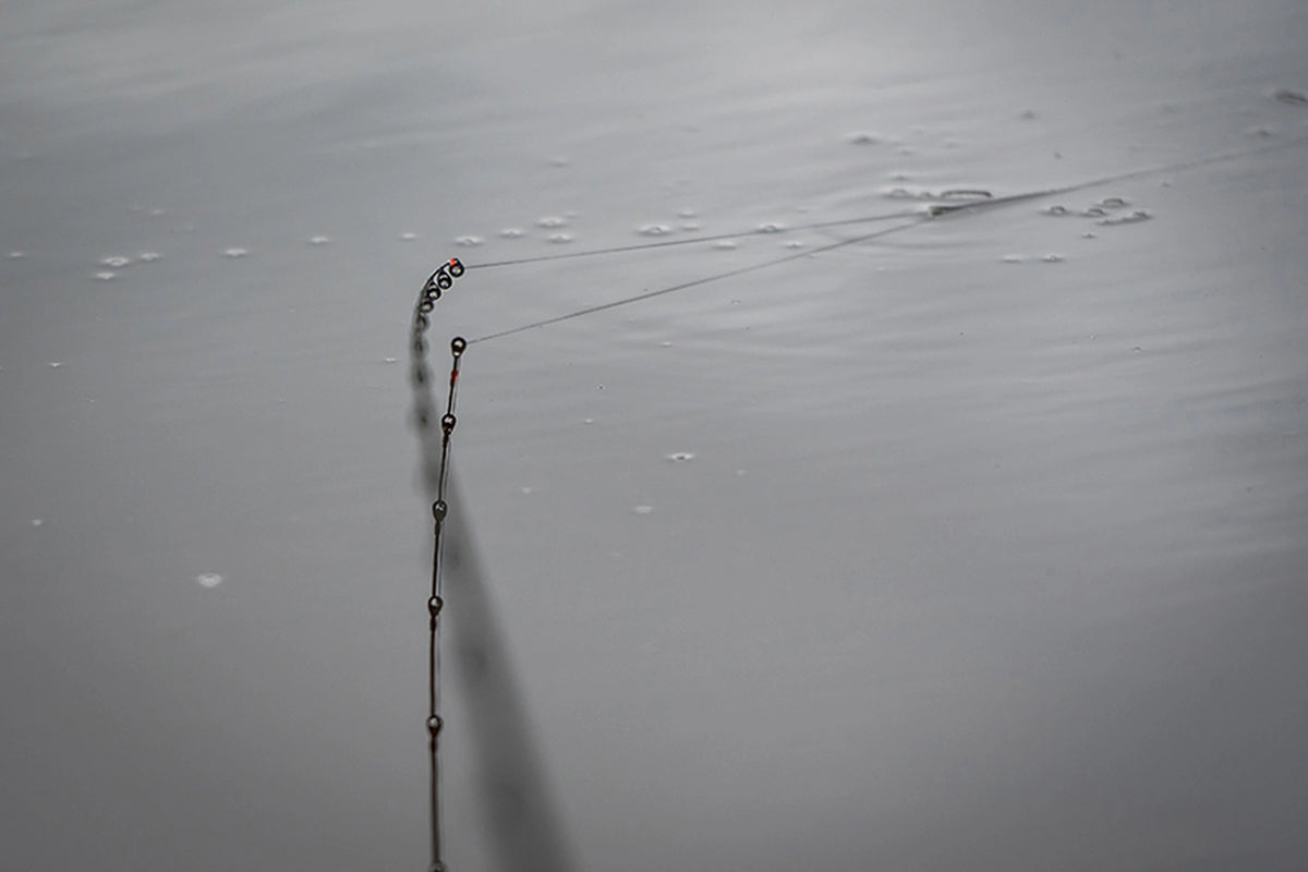 Matrix Ethos XR-S Feeder Rod – twee hengeltoppen met geleideogen en vislijnen vlak boven het grijze wateroppervlak