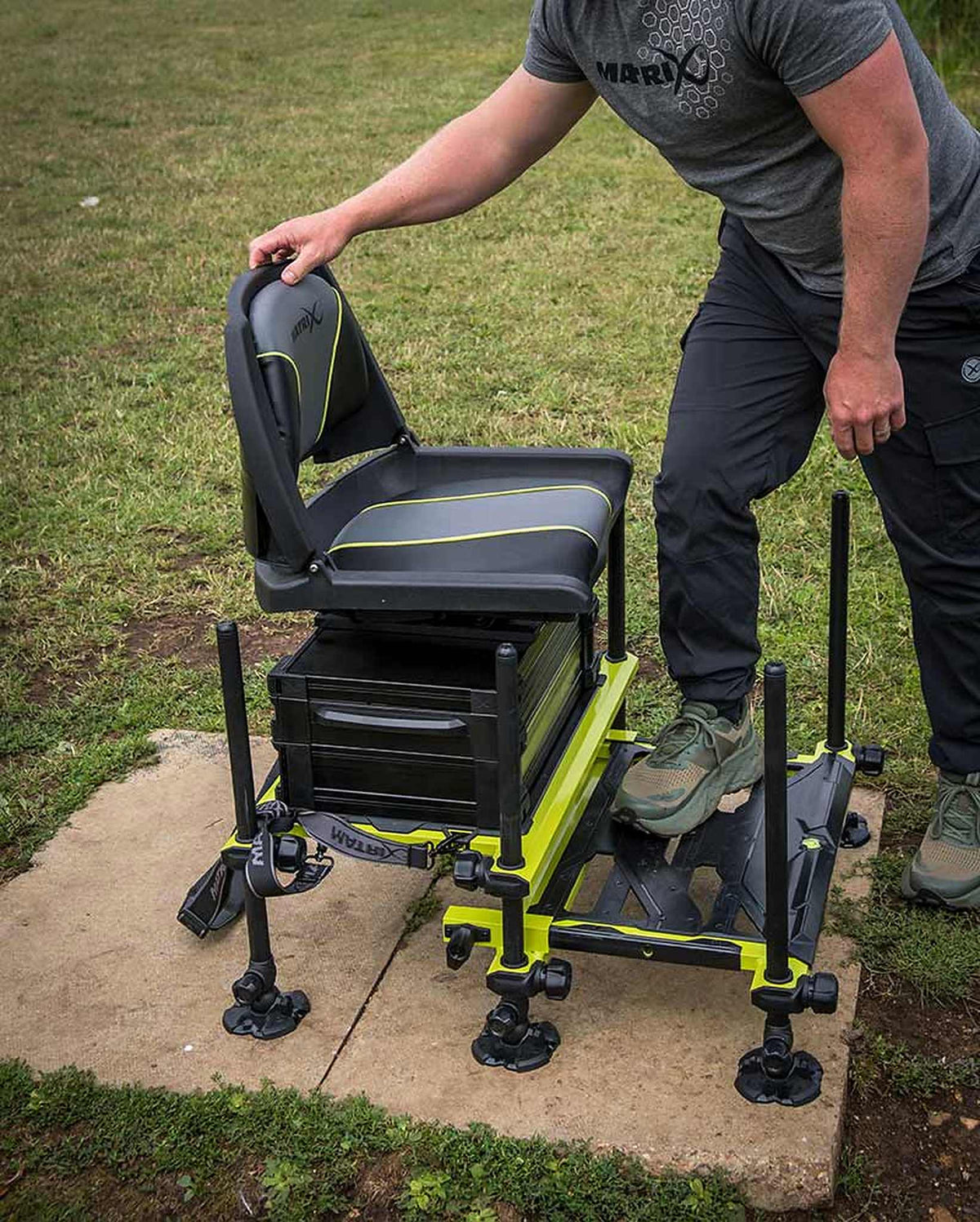 Matrix F25 Pro Swivel Seatbox Lime Edition met visser die de stoel verstelt aan de waterkant