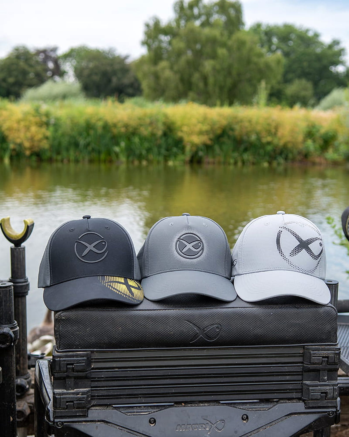 Matrix Faded Print Cap Black links naast twee andere Matrix-petten op een zitkist aan de waterkant