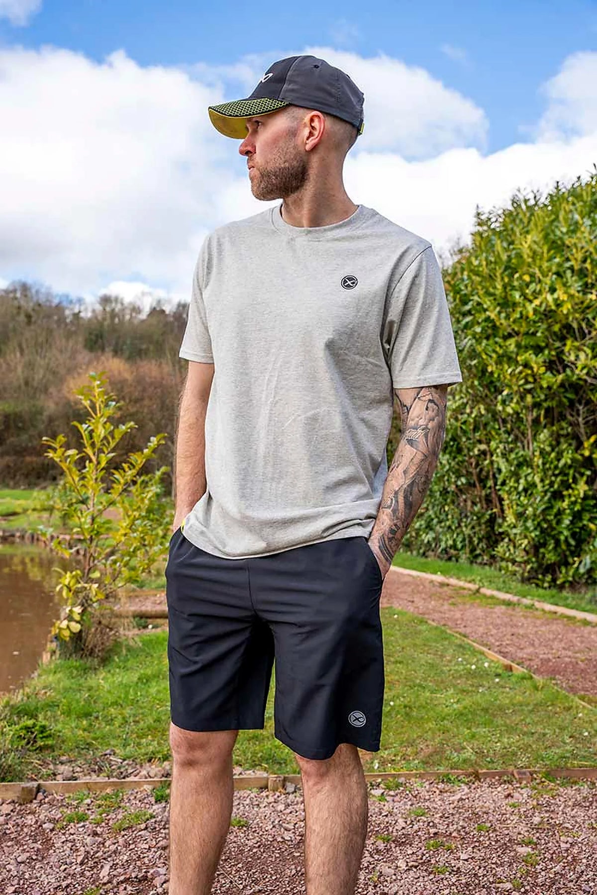 Matrix Grey Mini Logo T-shirt – model met pet kijkt opzij tijdens een buitenopname van de voorzijde en pasvorm van het shirt