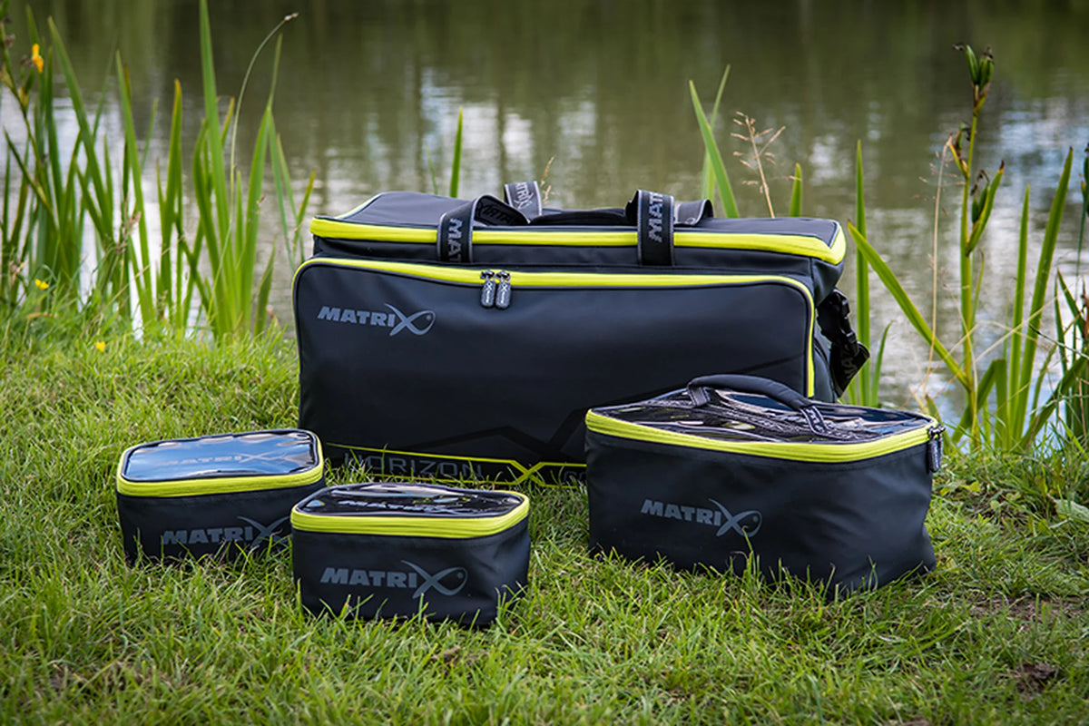Matrix Horizon X Compact Carryall – draagtas met drie opbergtasjes in het gras aan de waterkant
