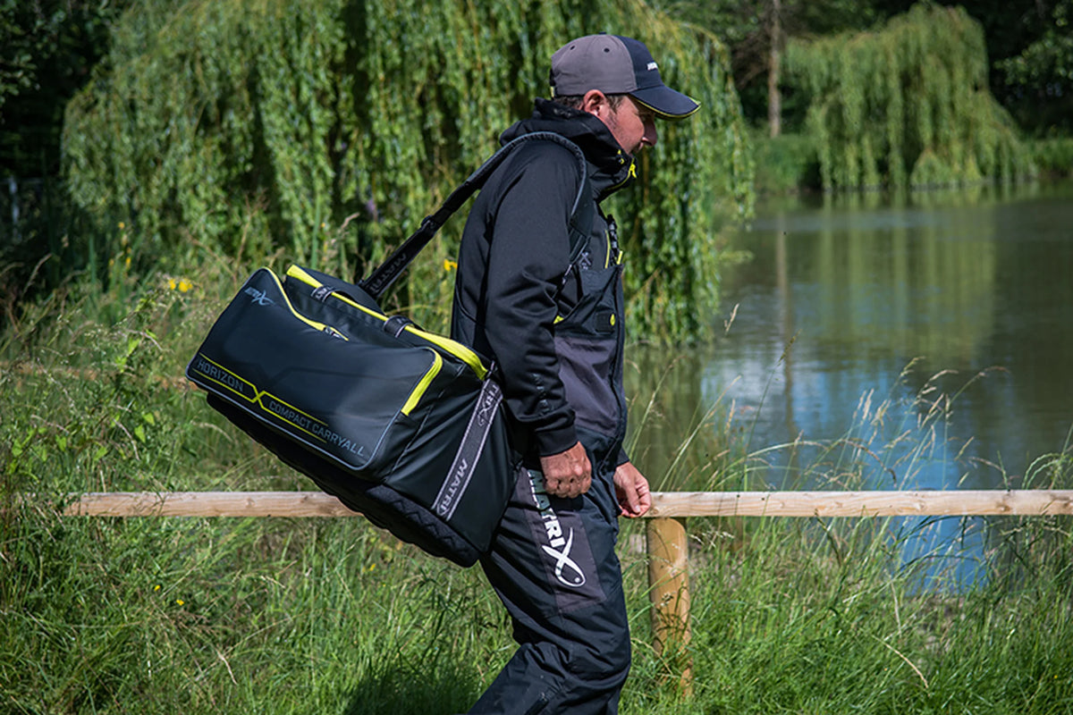 Matrix Horizon X Compact Carryall – visser draagt de tas over zijn schouder langs de waterkant