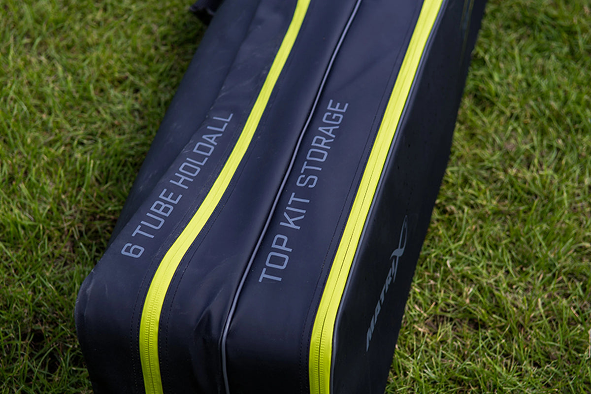 Matrix Horizon X Multi Pole Holdall – vakbedrukking 6 Tube Holdall en Top Kit Storage naast de gele ritsen in het gras