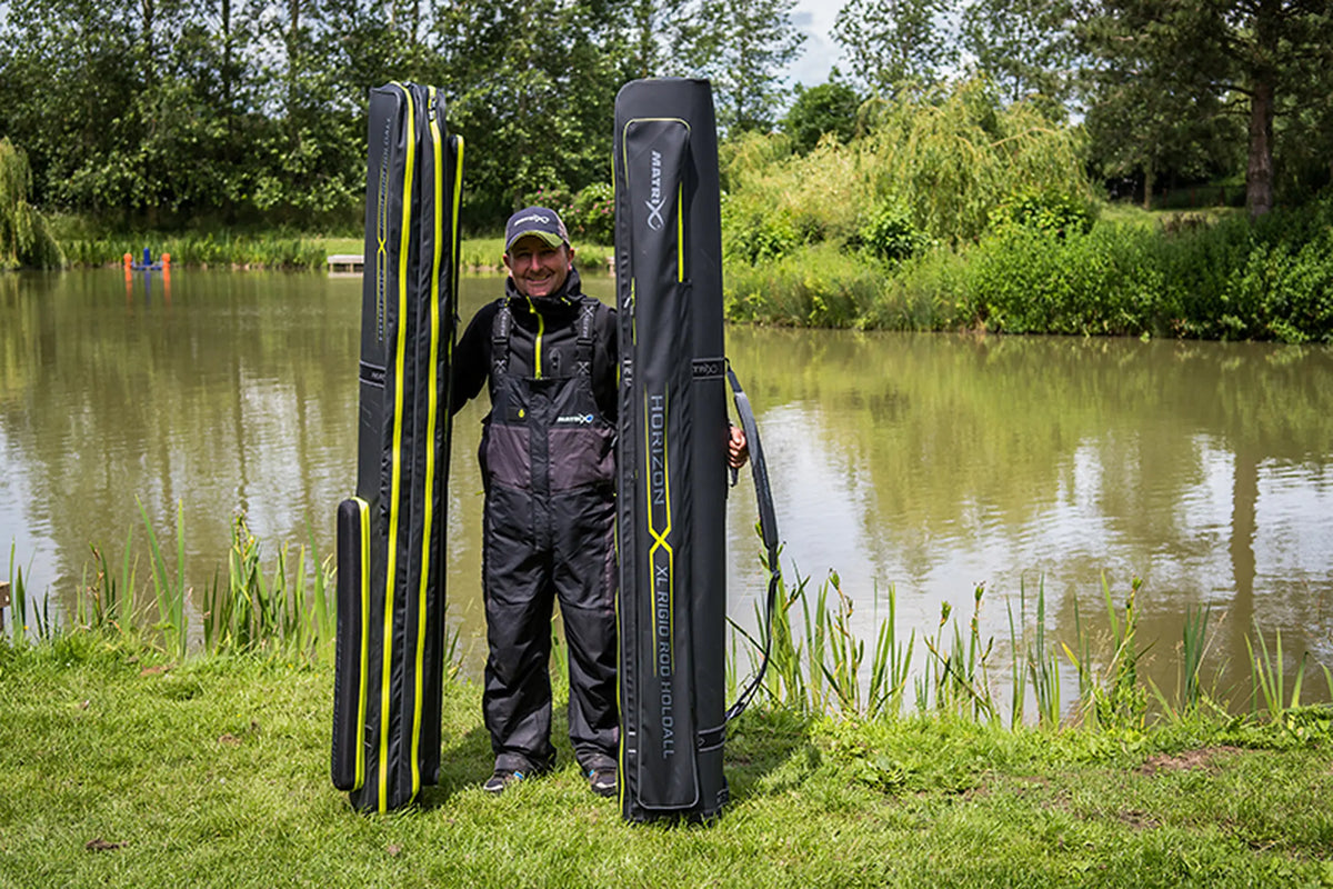 Matrix Horizon X Rigid Rod Holdall 2-4 – visser toont het 2-4-foedraal links naast het XL Rigid Rod Holdall aan de waterkant