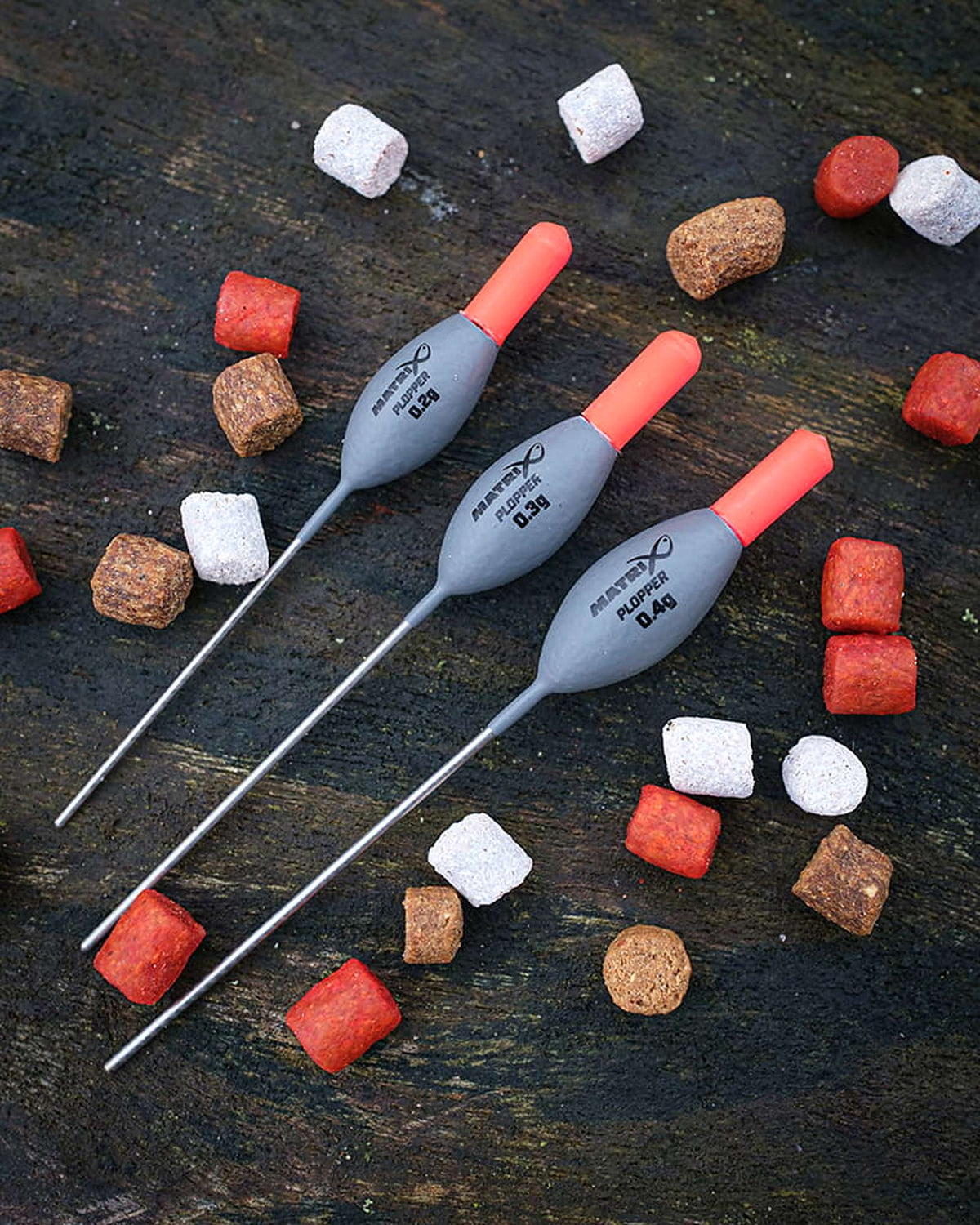 Matrix Plopper Pole Floats – drie dobbers met volledige onderstelen op hout tussen rode, witte en bruine aasjes