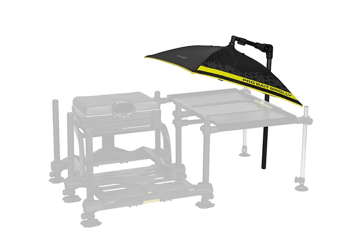 Matrix Pro Bait Brolly aasparaplu – lage positie vlak boven een lichtgrijs weergegeven aastafel naast de zitkist