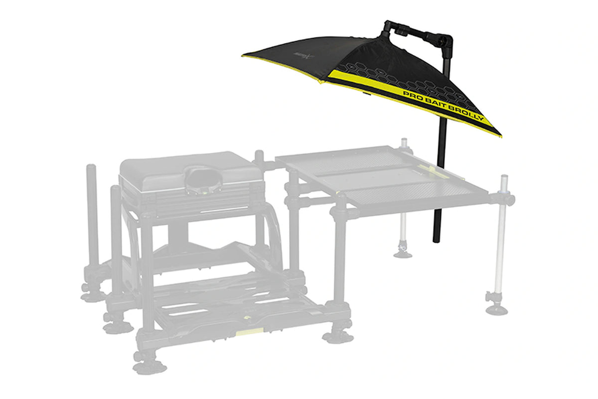 Matrix Pro Bait Brolly aasparaplu – middenpositie met verstelbare steunarm boven een lichtgrijs weergegeven zitkist en aastafel