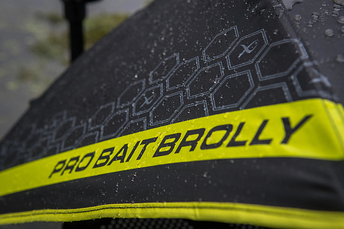 Matrix Pro Bait Brolly – close-up van de natte zwarte kap met honingraatpatroon en PRO BAIT BROLLY-opdruk op de gele strook