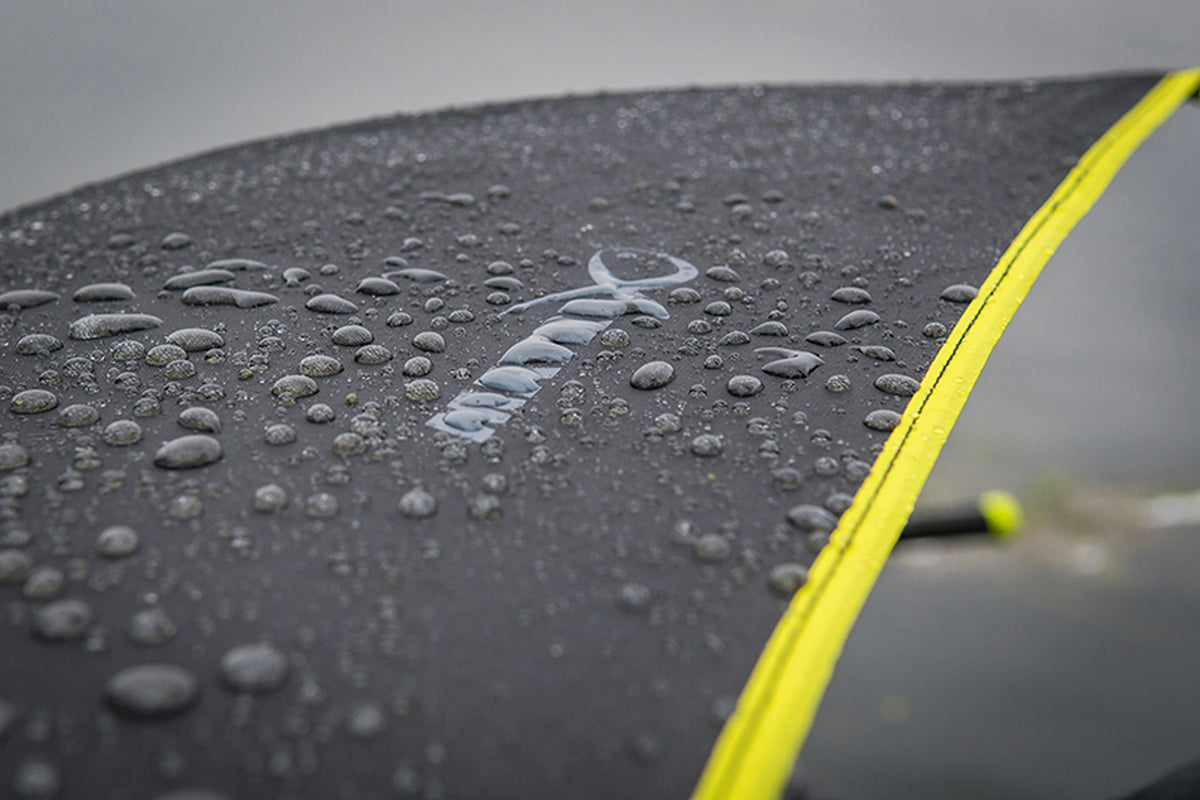 Matrix Pro Bait Brolly – close-up van waterdruppels op de zwarte paraplukap met Matrix-logo en gele rand