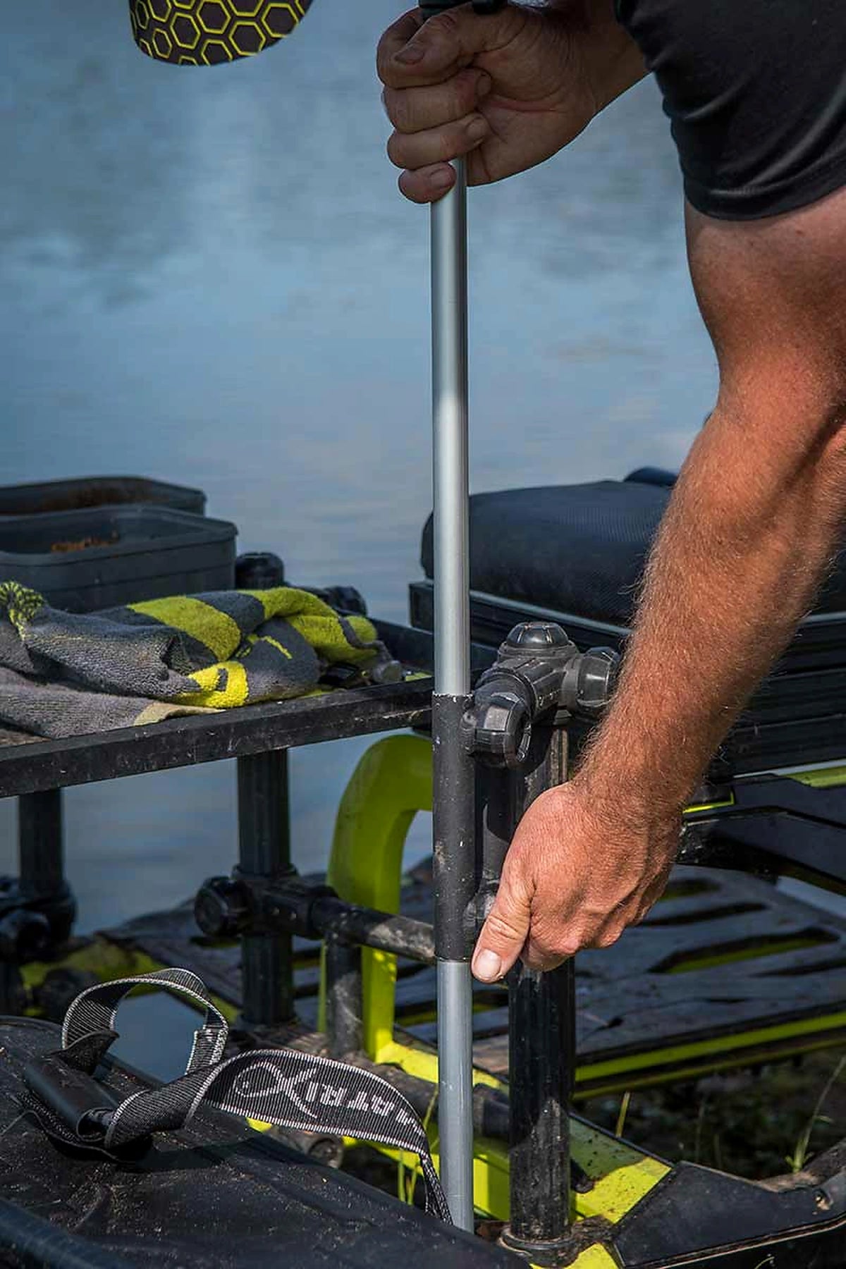 Matrix Pro Over Brolly 45 Inch – visser stelt de zilverkleurige paraplusteel af bij de bevestiging naast zijn zitkist
