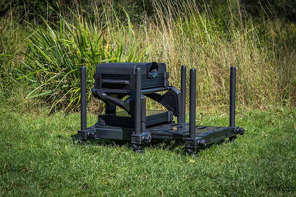 Matrix S36 Pro Black zitkist schuin van opzij op gras met uitgeschoven voetplaat en oeverplanten