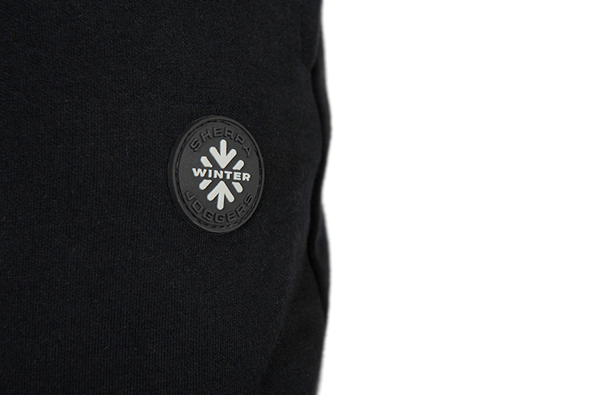 Matrix Sherpa Joggers – close-up van de zwarte ronde badge met SHERPA, WINTER en JOGGERS op de zwarte stof