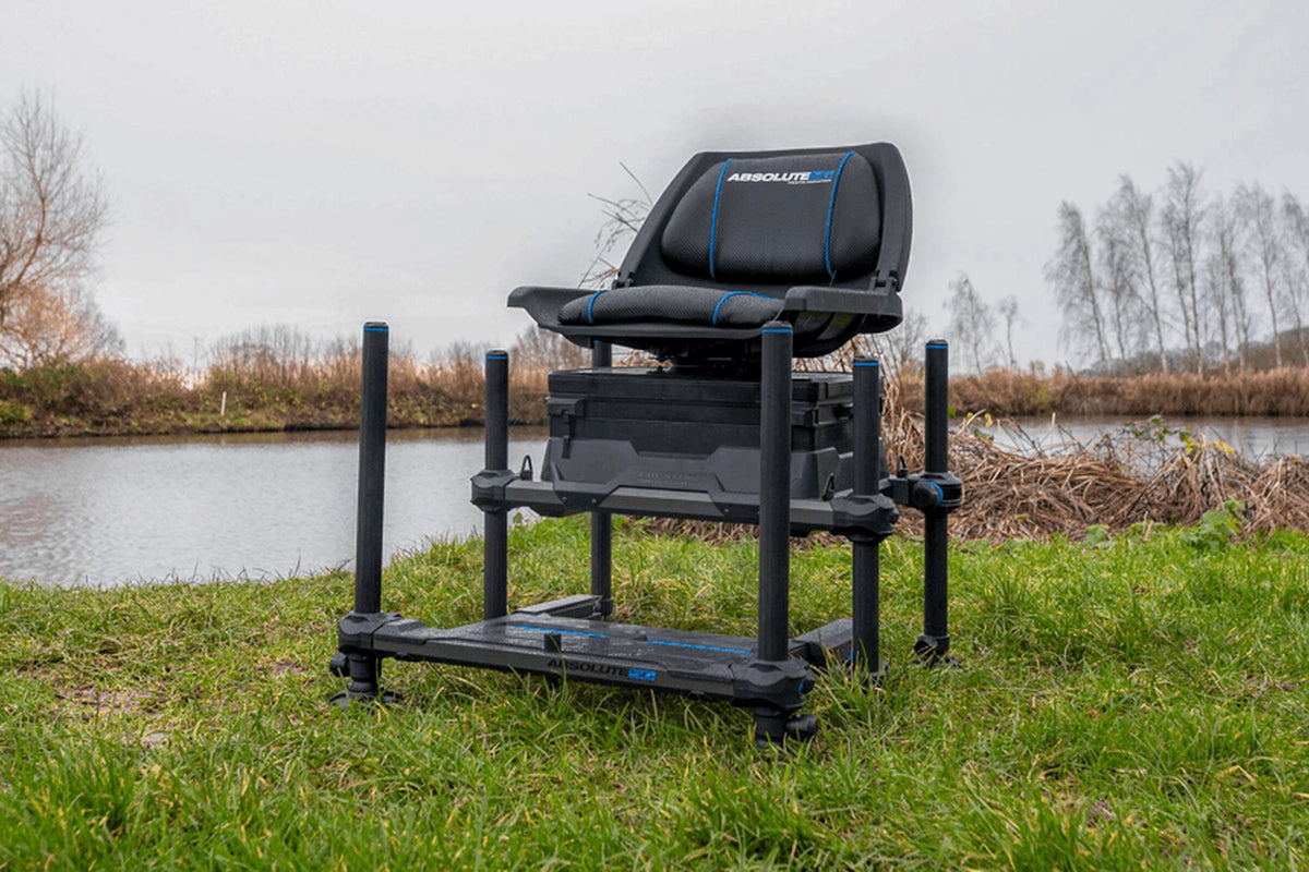 Preston Absolute 5G 360-zitkist met draaistoel en uitgeschoven voetplaat op de grasbank aan de waterkant