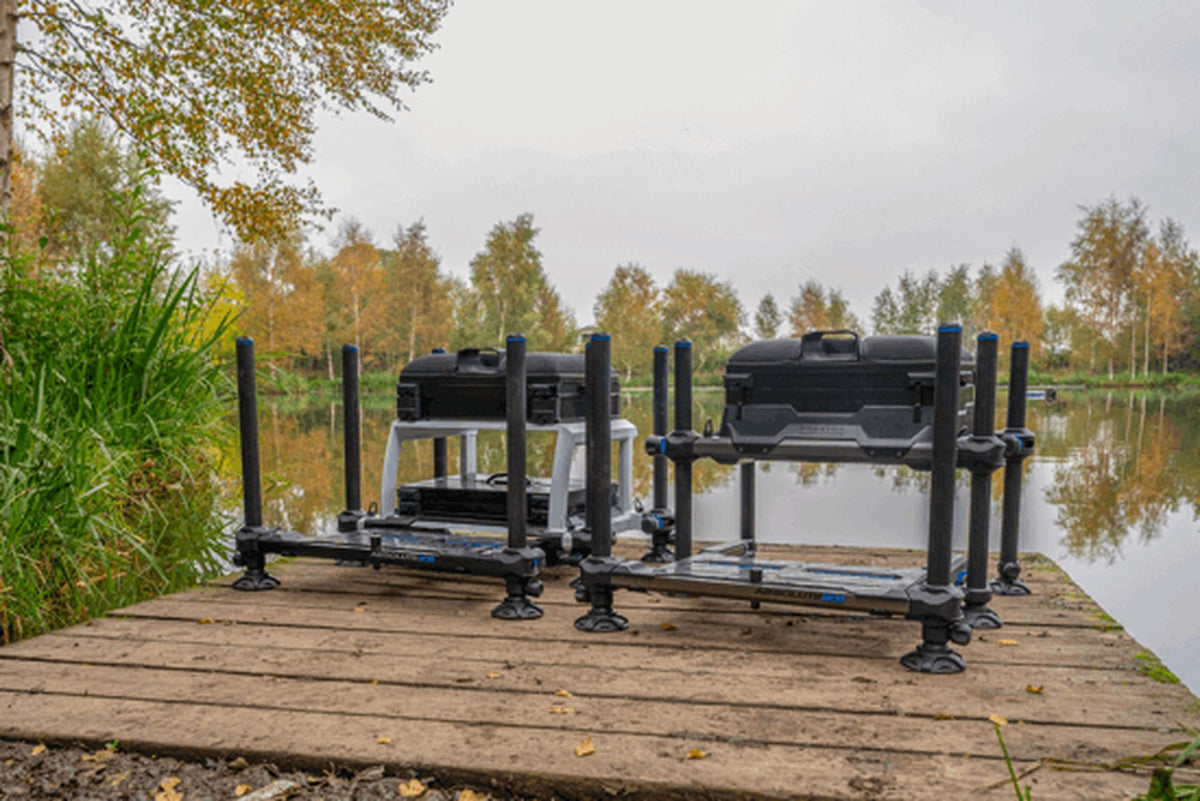 Preston Absolute 5G Station – vergelijking van de zwarte en zilverkleurige zitkist aan het water, vanaf de voorkant gezien