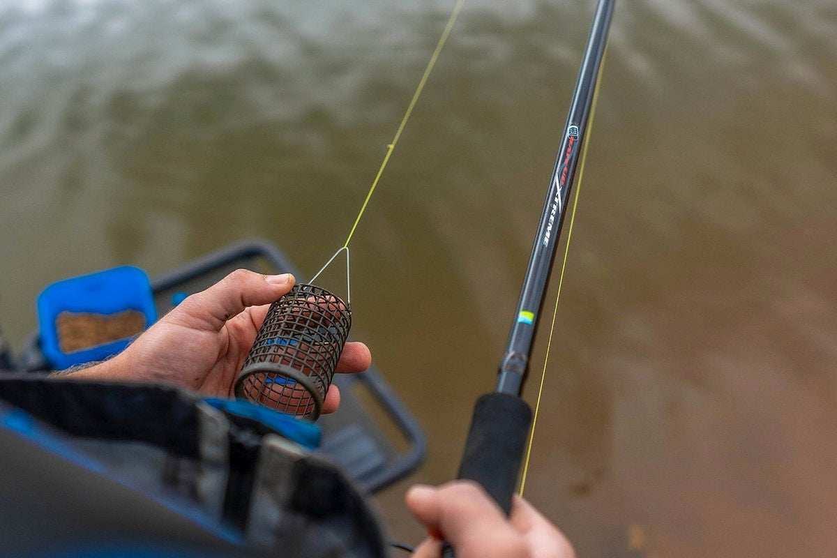 Preston Bait Up Xtreme voerhengel – visser houdt een lege voerkorf naast de hengel vast
