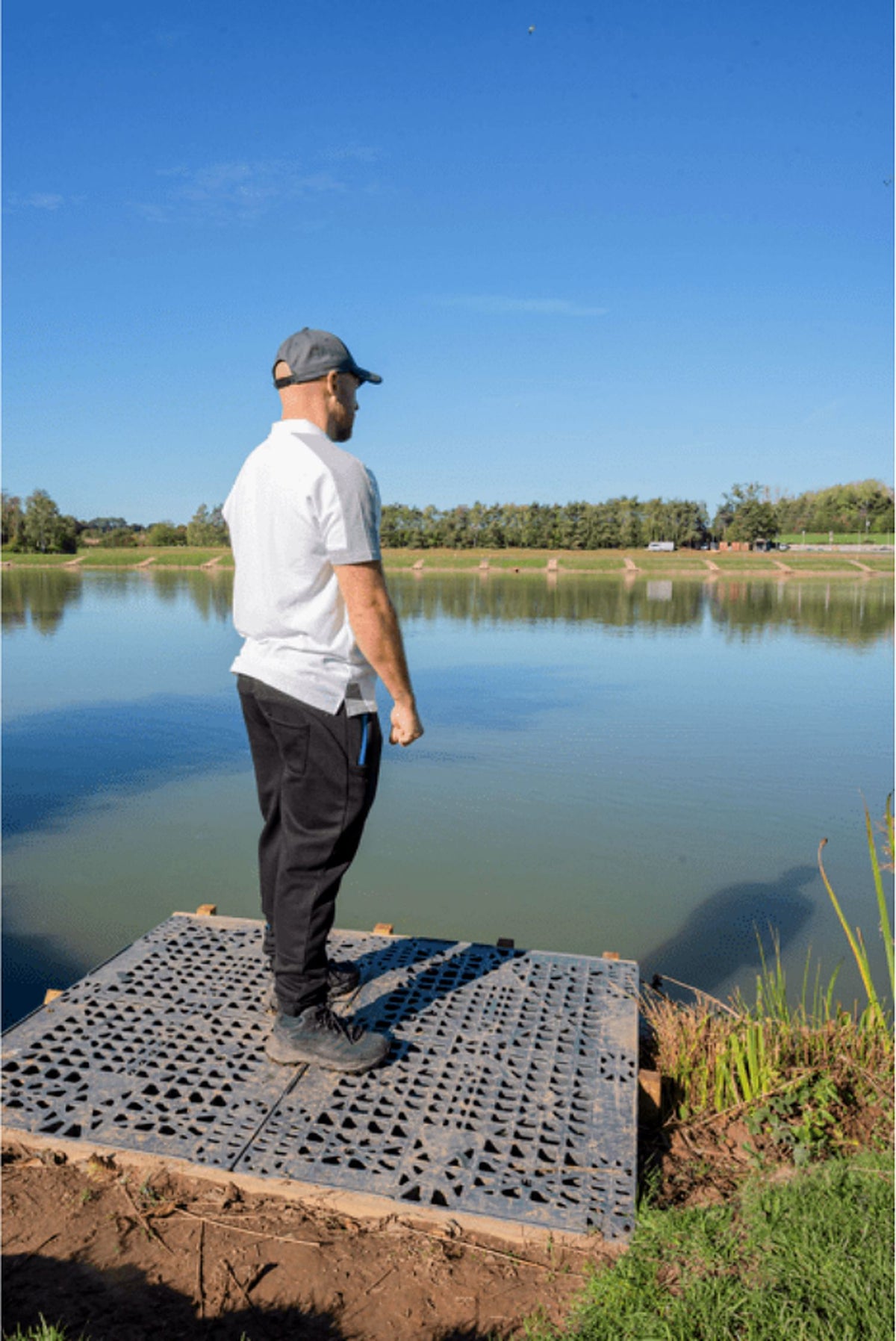 Preston Core Collection Polo White – polo gedragen in zijaanzicht door een visser op een steiger aan het water