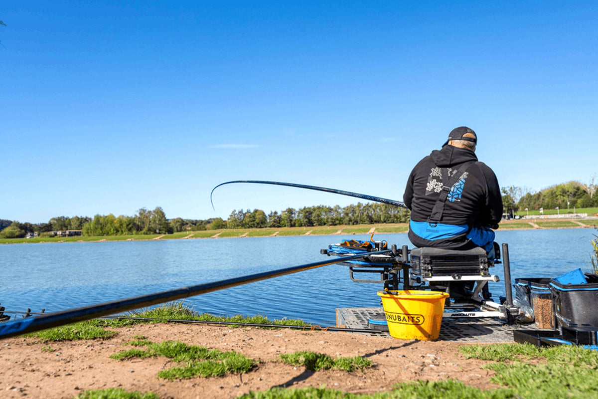 Preston Edge Monster Margin 11m – achteraanzicht van de visser op de zitkist met hengel boven het water