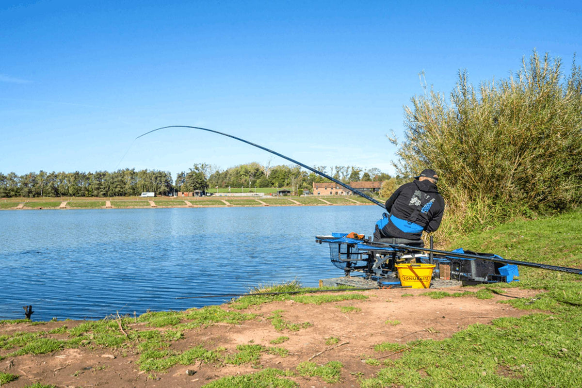 Preston Edge Monster Margin 11m – visser naast een struik met de hengel onder belasting boven het water