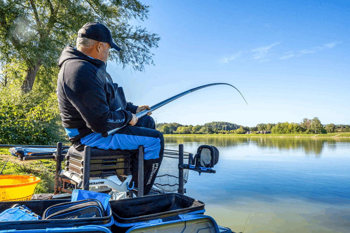 Preston Edge Monster Margin 11m – visser met gebogen kanthengel vanaf een zitkist aan het water