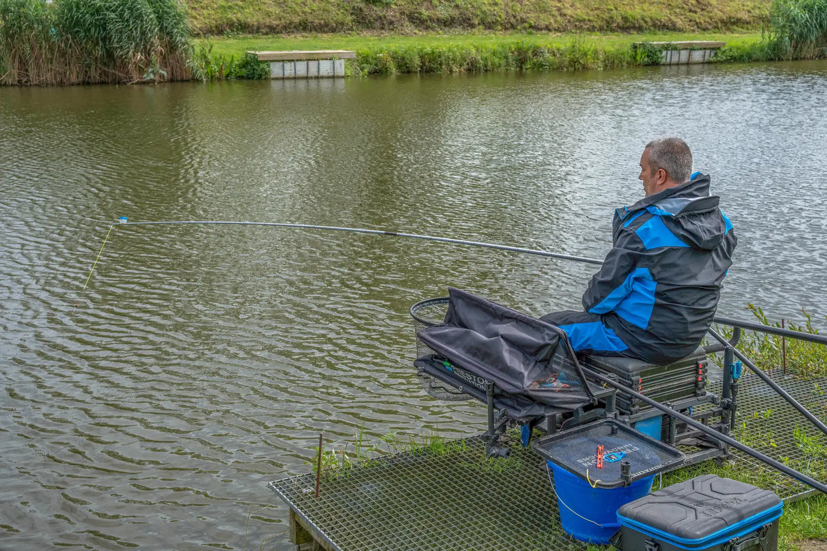 Visser gebruikt de Preston Euro Carp 1150 STR S vanaf een zitkist aan het water