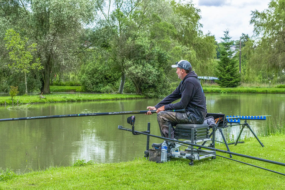 Visser met de Preston Euro Carp 1150 STR S vanaf een zitkist, gezien vanaf de zijkant