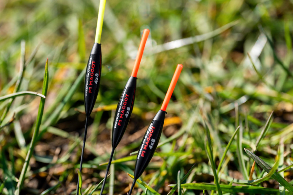 Drie Preston F1 Maggot 4x8 dobbers met rode en gele antennes in het gras